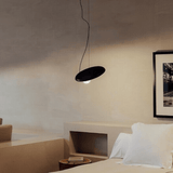 Modern bedroom with a black pendant light and framed artwork on the wall.