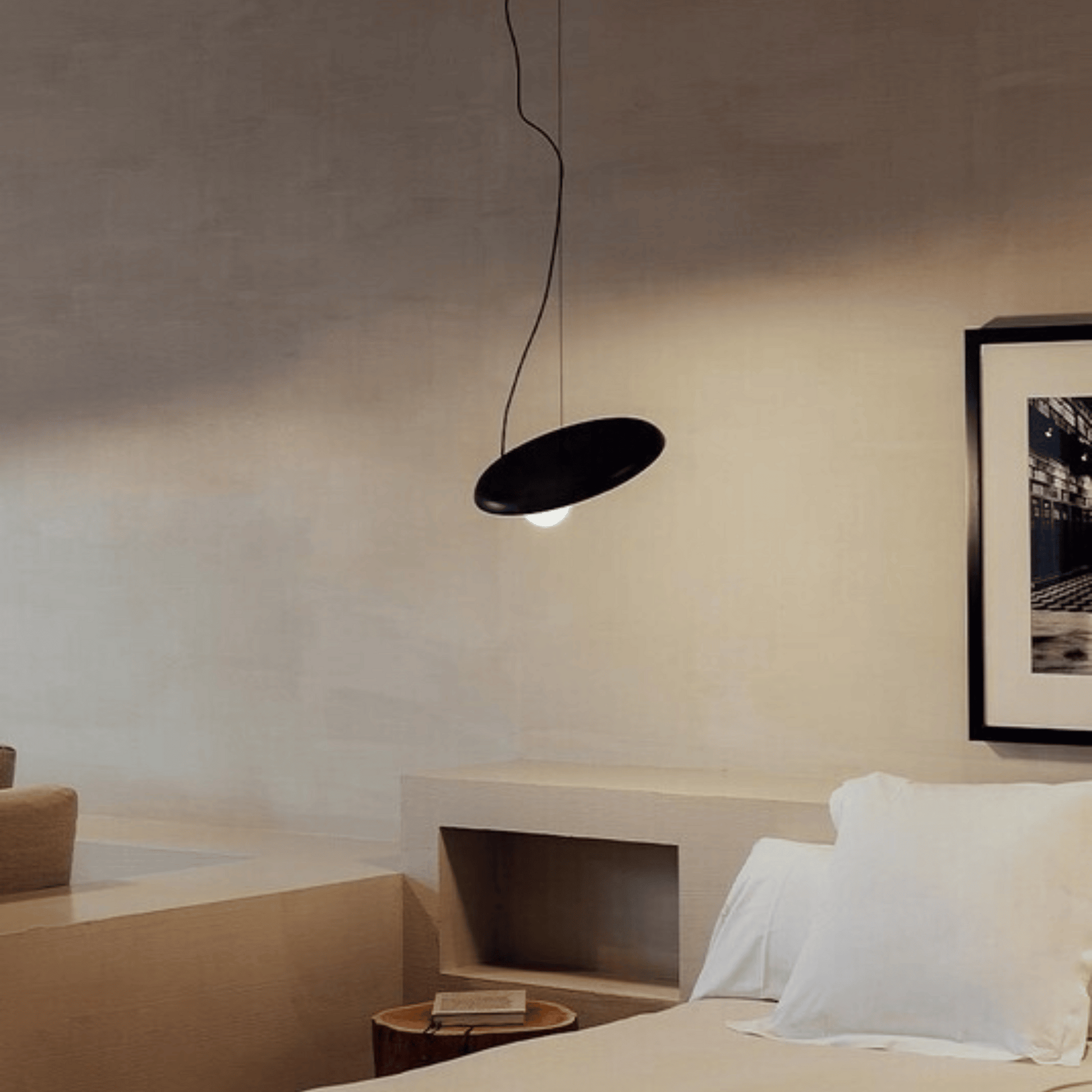 Modern bedroom with a black pendant light and framed artwork on the wall.