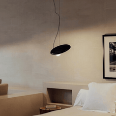 Modern bedroom with a black pendant light and framed artwork on the wall.