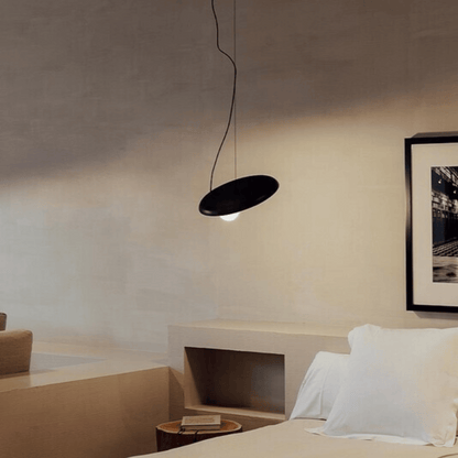 Modern bedroom with a black pendant light and framed artwork on the wall.