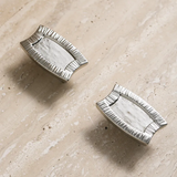 Two silver decorative items on a beige stone surface