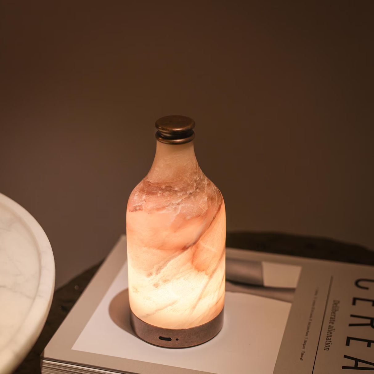 Marble-textured bottle-shaped lamp on a surface with a warm glow