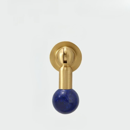 Modern brass knob featuring a deep blue gemstone sphere handle isolated on white background.