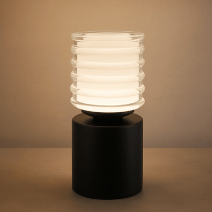 Table lamp with ribbed glass shade on a black base against a beige background