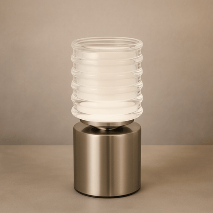 Table lamp with ribbed glass shade and metallic base on a beige background