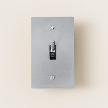 Gray light switch plate with a black toggle switch on a beige background
