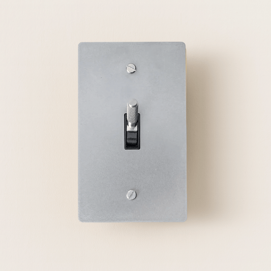 Gray light switch plate with a black toggle switch on a beige background