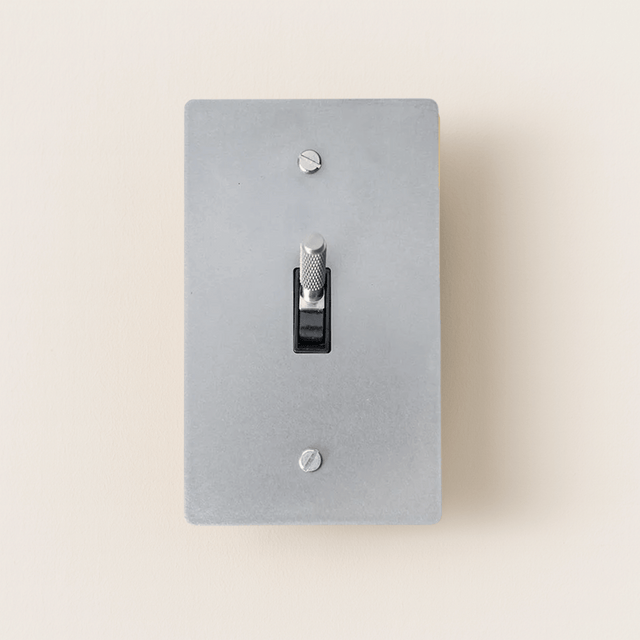 Gray light switch plate with a black toggle switch on a beige background
