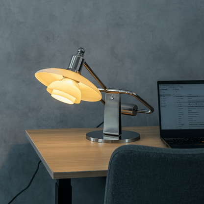 Desk setup with a lamp and laptop on a wooden desk against a gray wall.