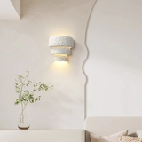 Decorative wall sconce with a vase of greenery on a white wall.