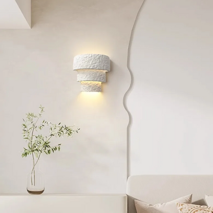 Decorative wall sconce with a vase of greenery on a white wall.