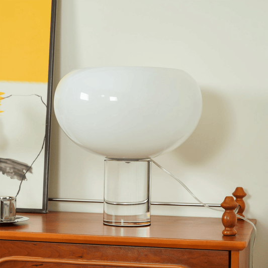 Modern table lamp with a white glass shade on a wooden surface.