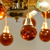 Close-up of a chandelier with orange glass bulbs and metallic fixtures.