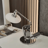 Modern desk lamp on a white surface with a magazine in the background