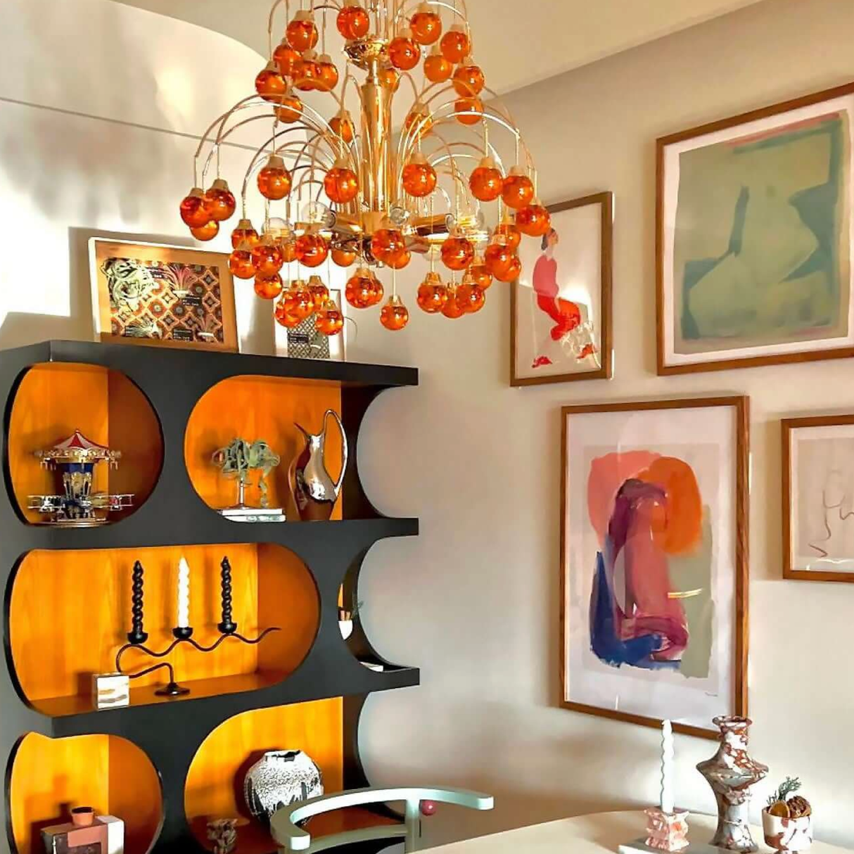 Decorative interior with orange chandelier, shelves, and wall art.