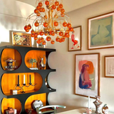 Decorative interior with orange chandelier, shelves, and wall art.