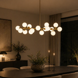 Modern chandelier hanging above a dining table in a dimly lit room.
