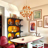 Modern dining room with a chandelier, table, chairs, and wall art.