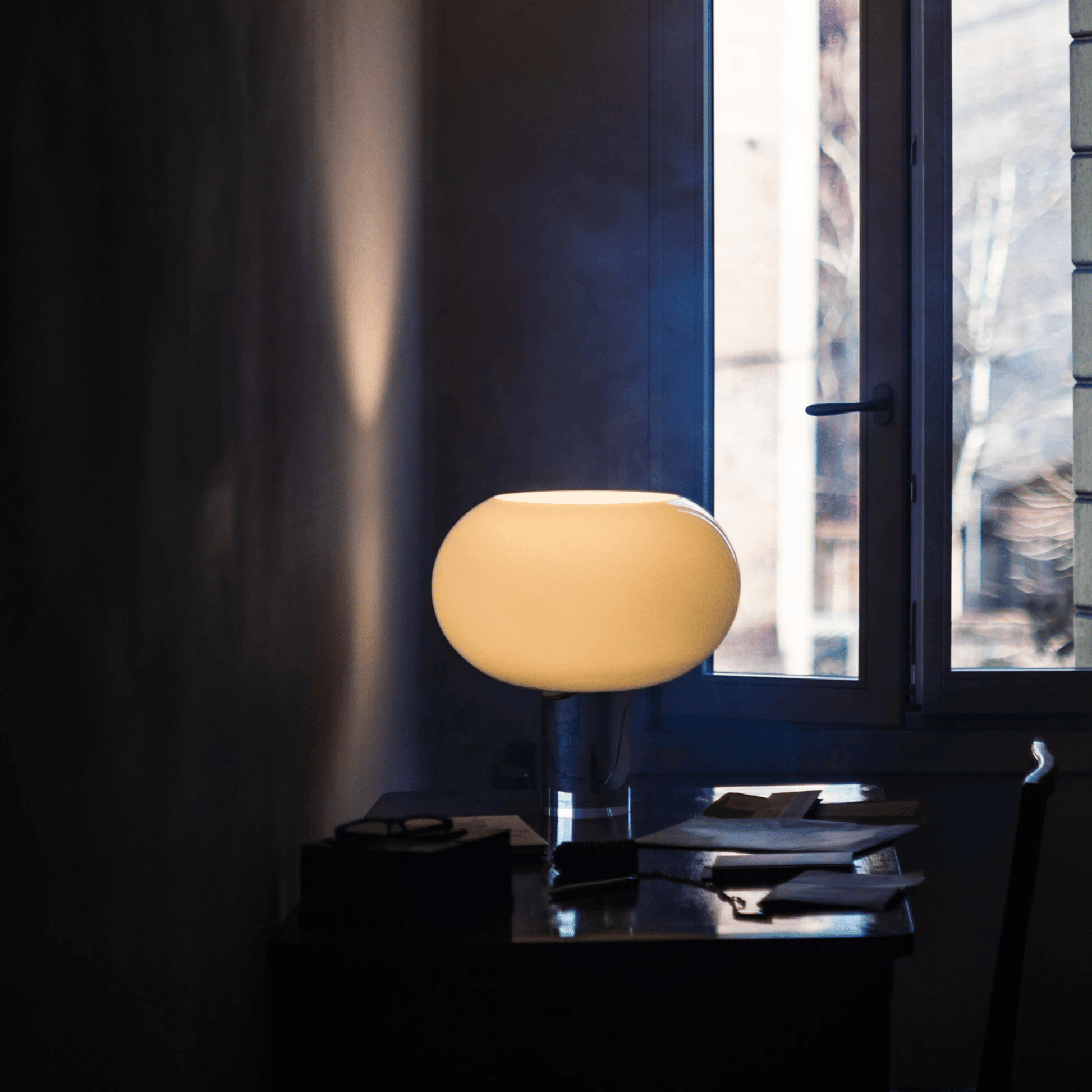 Small round lamp on a table with a window in the background