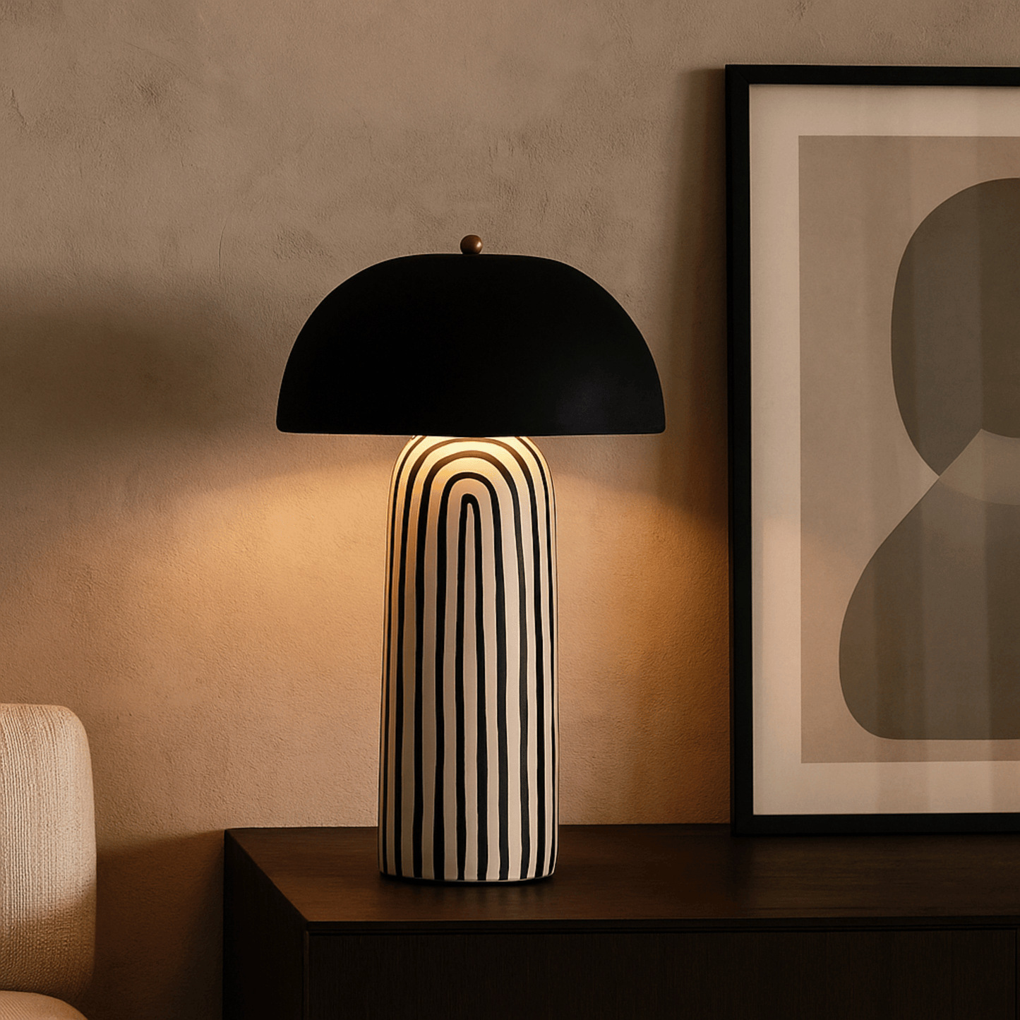 Black and white striped table lamp on a wooden surface with abstract art in the background.
