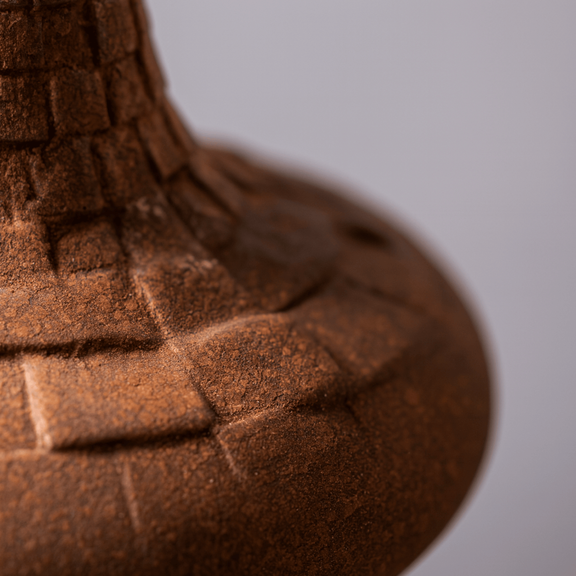 Close-up of a textured brown object with geometric patterns on a gray background