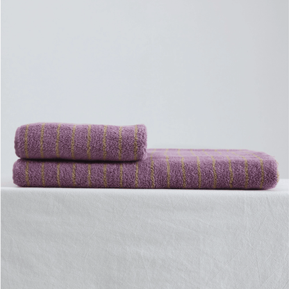 Two purple towels with gold stripes on a light gray background