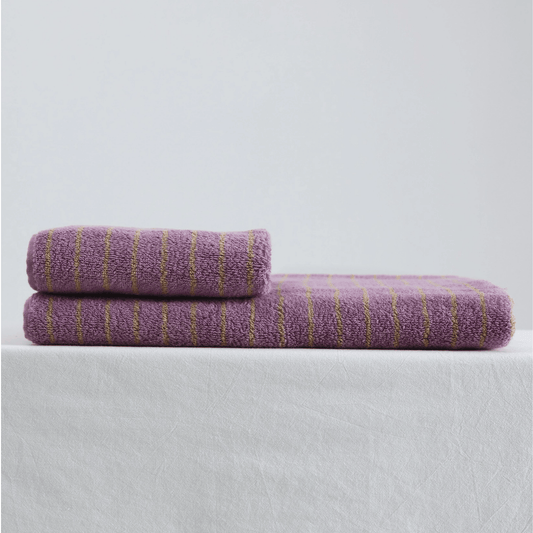 Two purple towels with gold stripes on a light gray background
