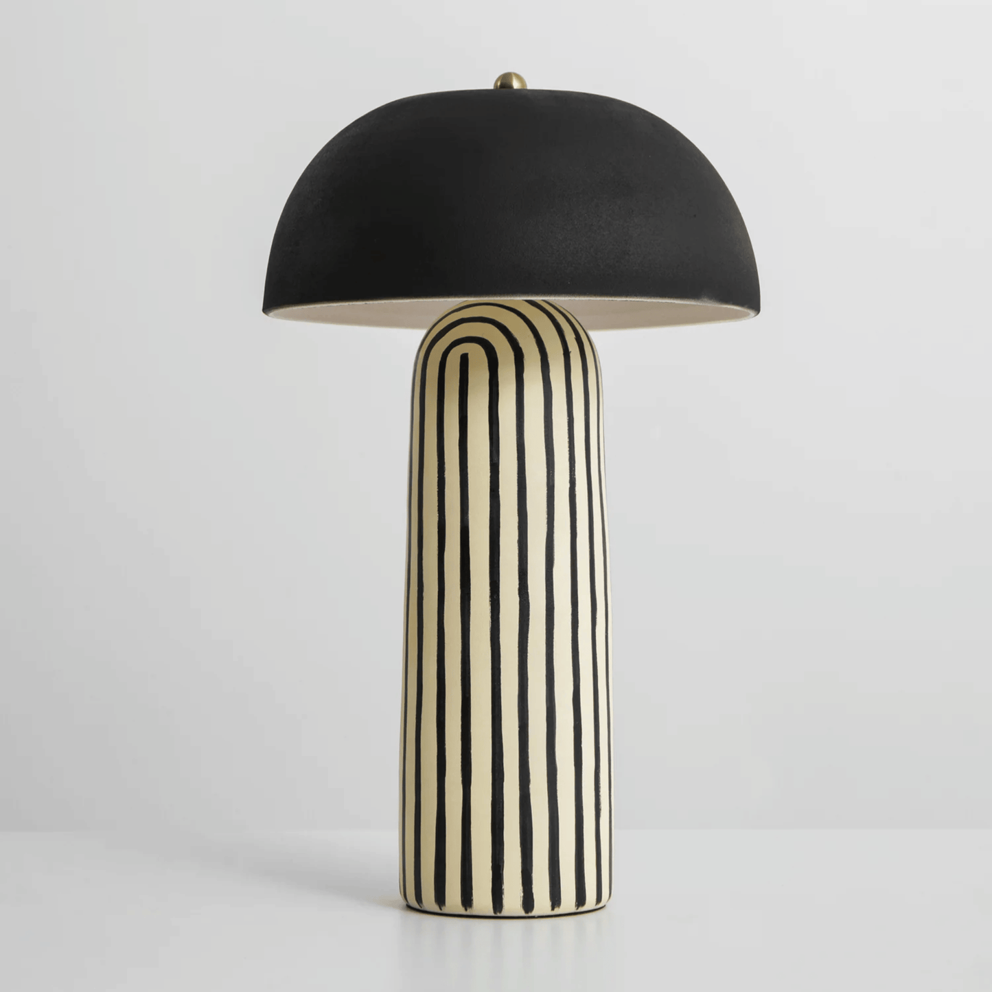 Table lamp with black umbrella shade and striped cylindrical base on a white background