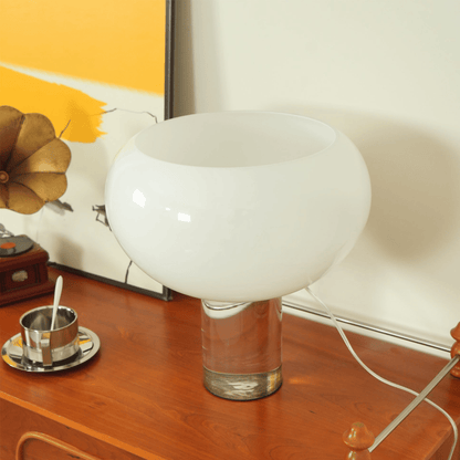 White glass table lamp on a wooden surface with a vintage gramophone in the background.