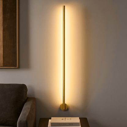Gold floor lamp casting a warm glow on a wall next to a sofa.