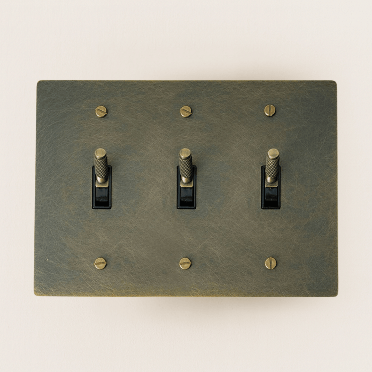 Switch plate with three toggle switches on a beige background