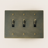 Switch plate with three toggle switches on a beige background