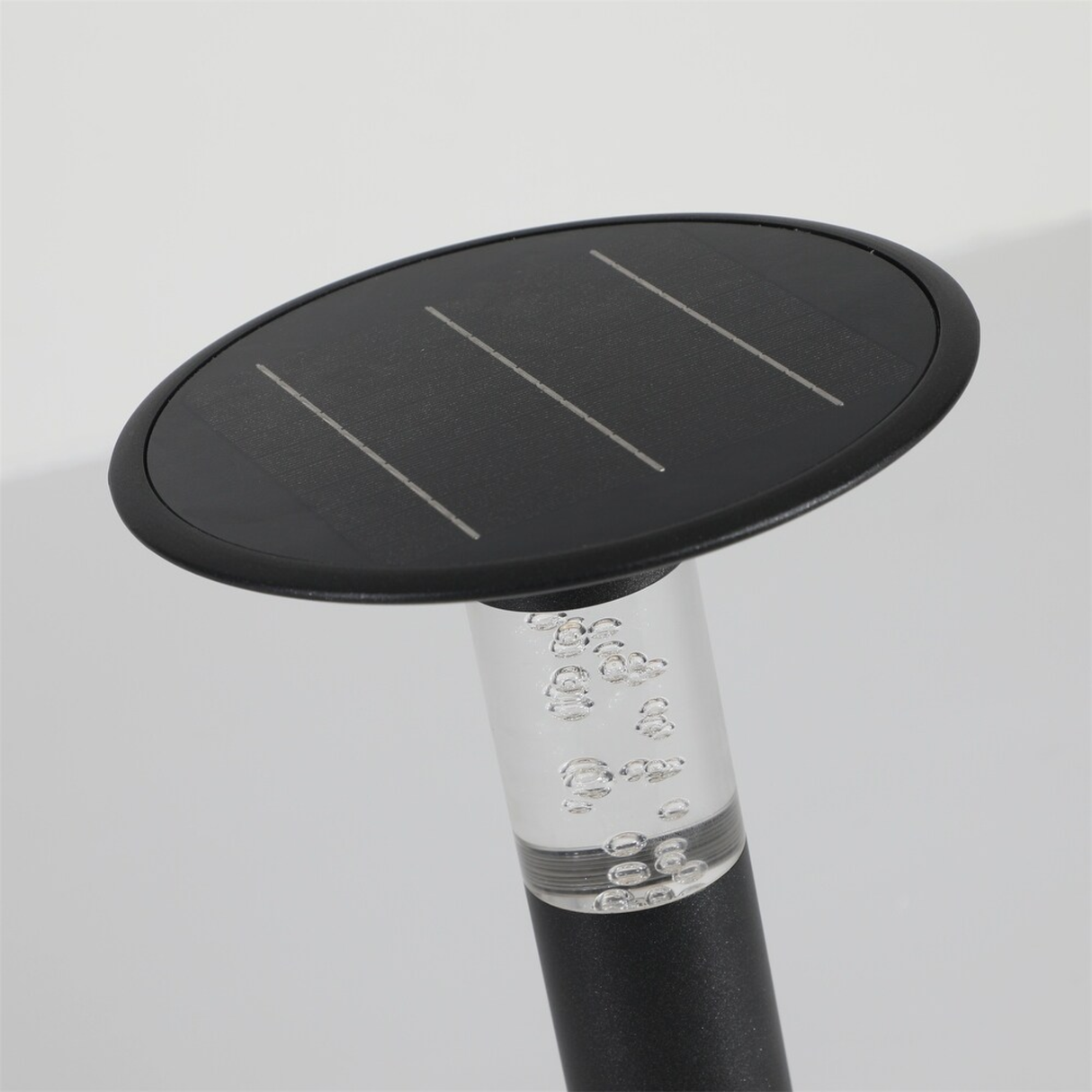 Solar panel on top of a clear bottle with black cap against a light gray background