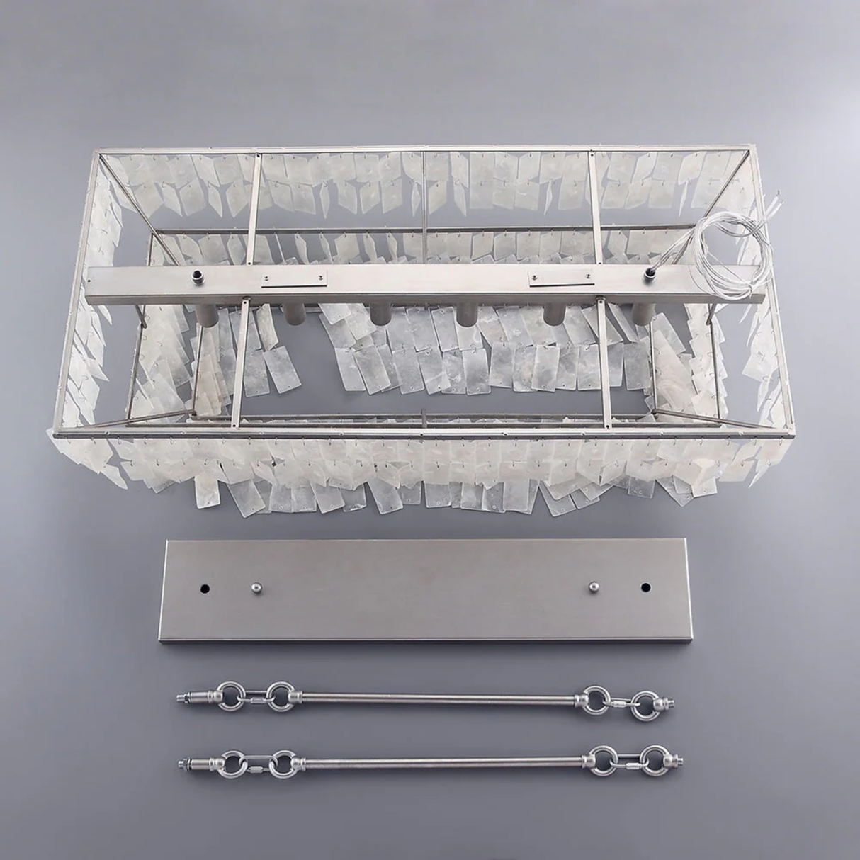 Decorative wall light fixture with clear glass shade and metal components on a gray background
