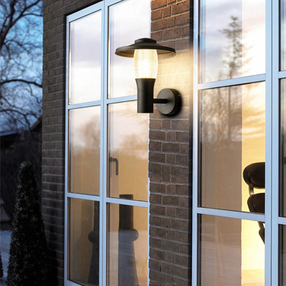 Elegant glass-walled exterior reflecting soft light from a modern outdoor wall sconce at dusk