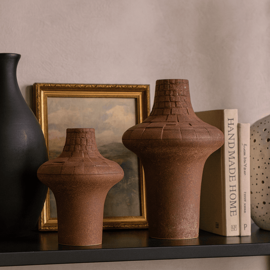 Decorative vases and a framed picture on a shelf against a neutral wall.