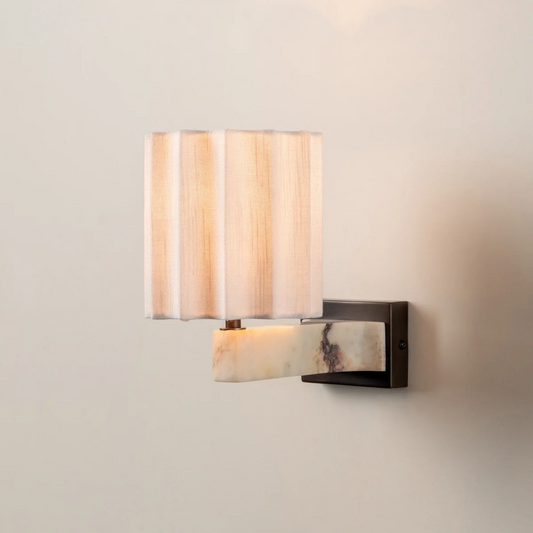 Wall-mounted light fixture with a striped lampshade on a neutral wall.