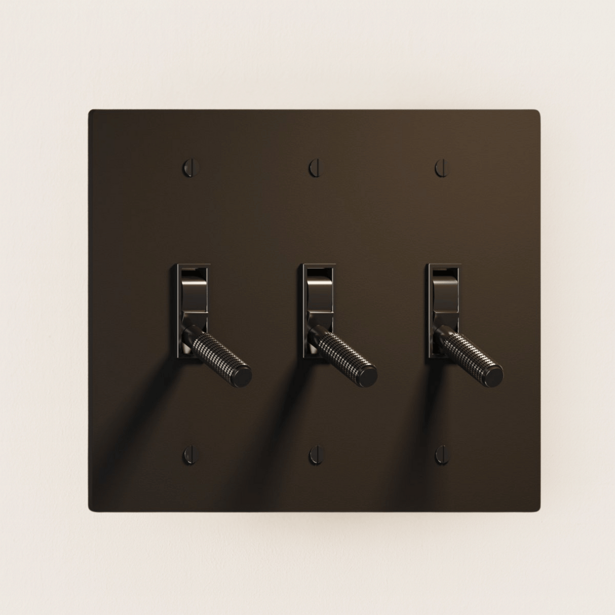 Dark brown wall plate with three toggle switches on a beige background