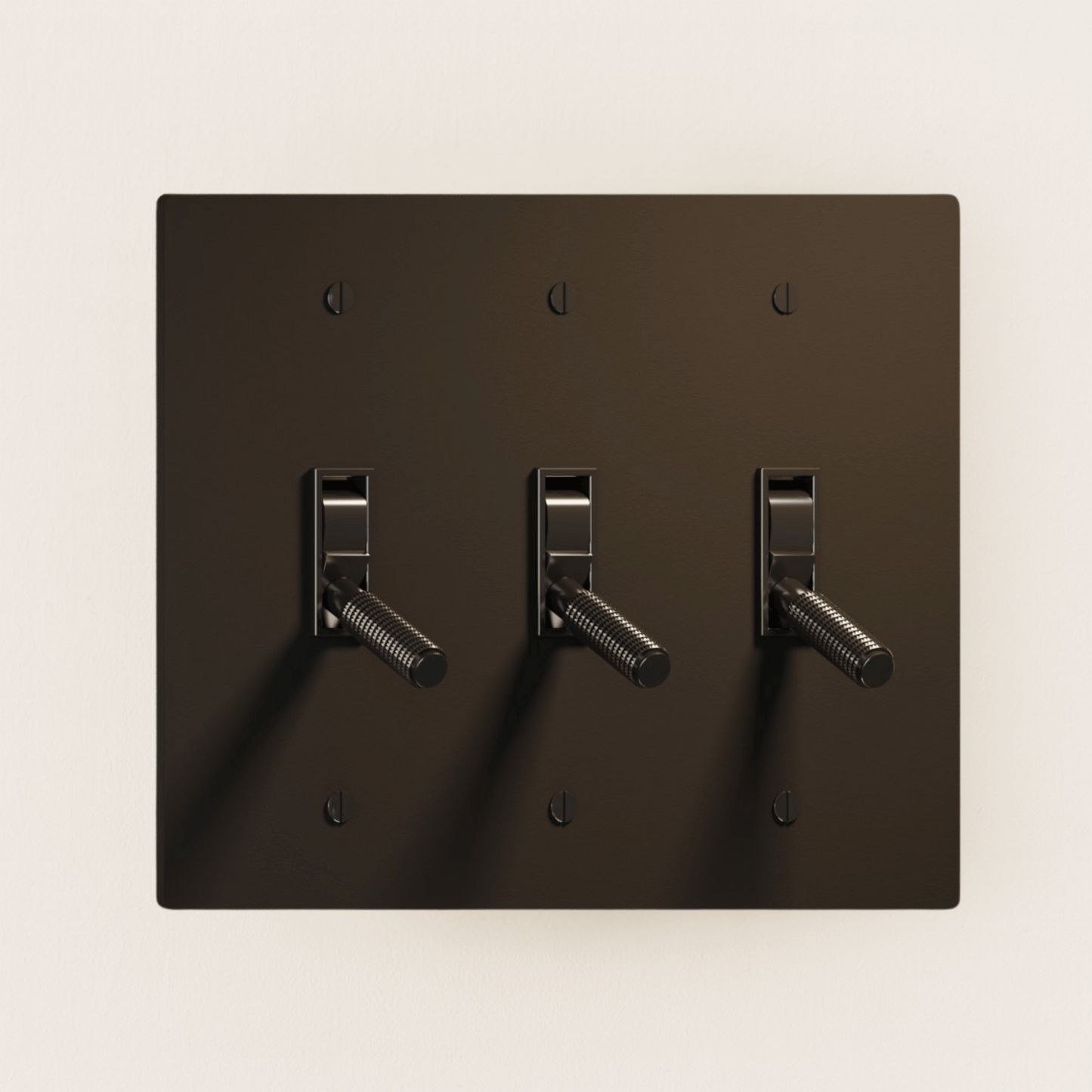 Dark brown wall plate with three toggle switches on a beige background