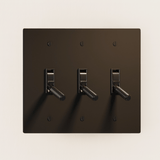 Dark brown wall plate with three toggle switches on a beige background