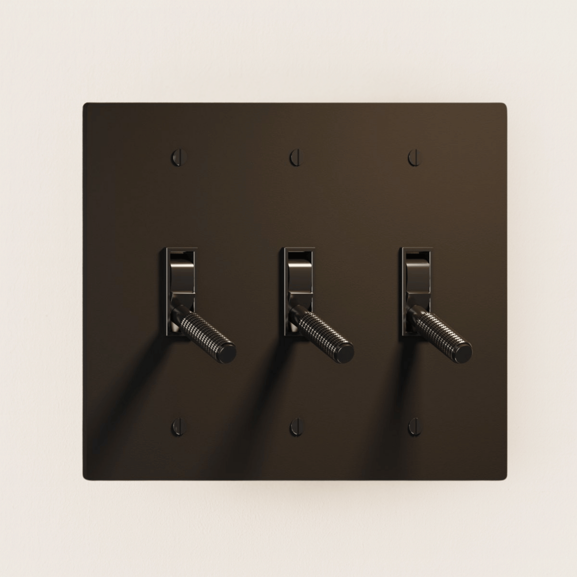 Dark brown wall plate with three toggle switches on a beige background