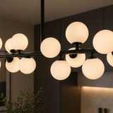 Modern chandelier with glass globe lights in a dimly lit room.