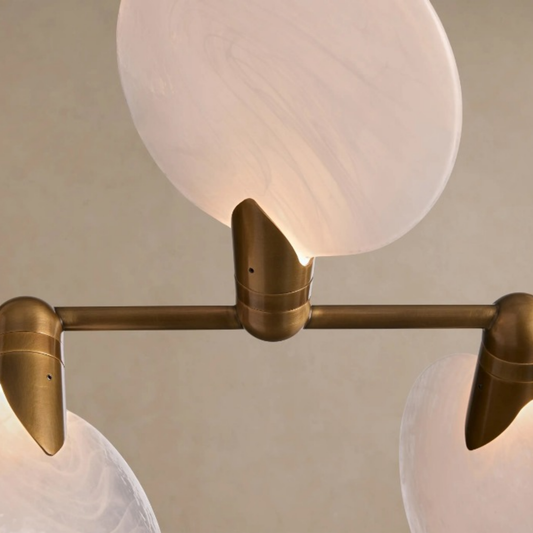 Modern wall light fixture with brass finish and glass shades on a neutral background