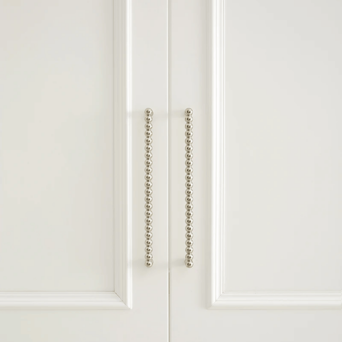 Close-up of a white cabinet door with decorative metal handle