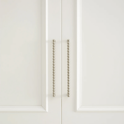 Close-up of a white cabinet door with decorative metal handle