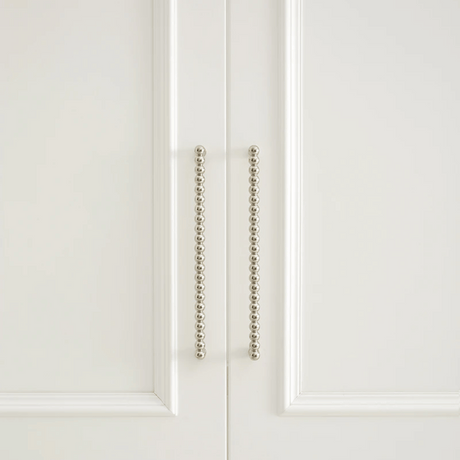 Close-up of a white cabinet door with decorative metal handle