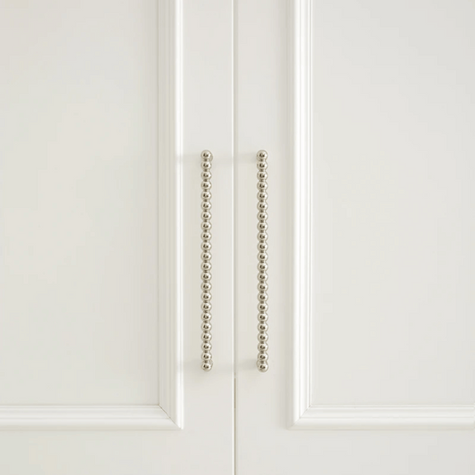 Close-up of a white cabinet door with decorative metal handle