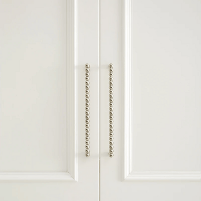 Close-up of a white cabinet door with decorative metal handle