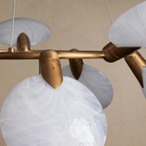 Chandelier with gold fixtures and white glass shades on a beige background