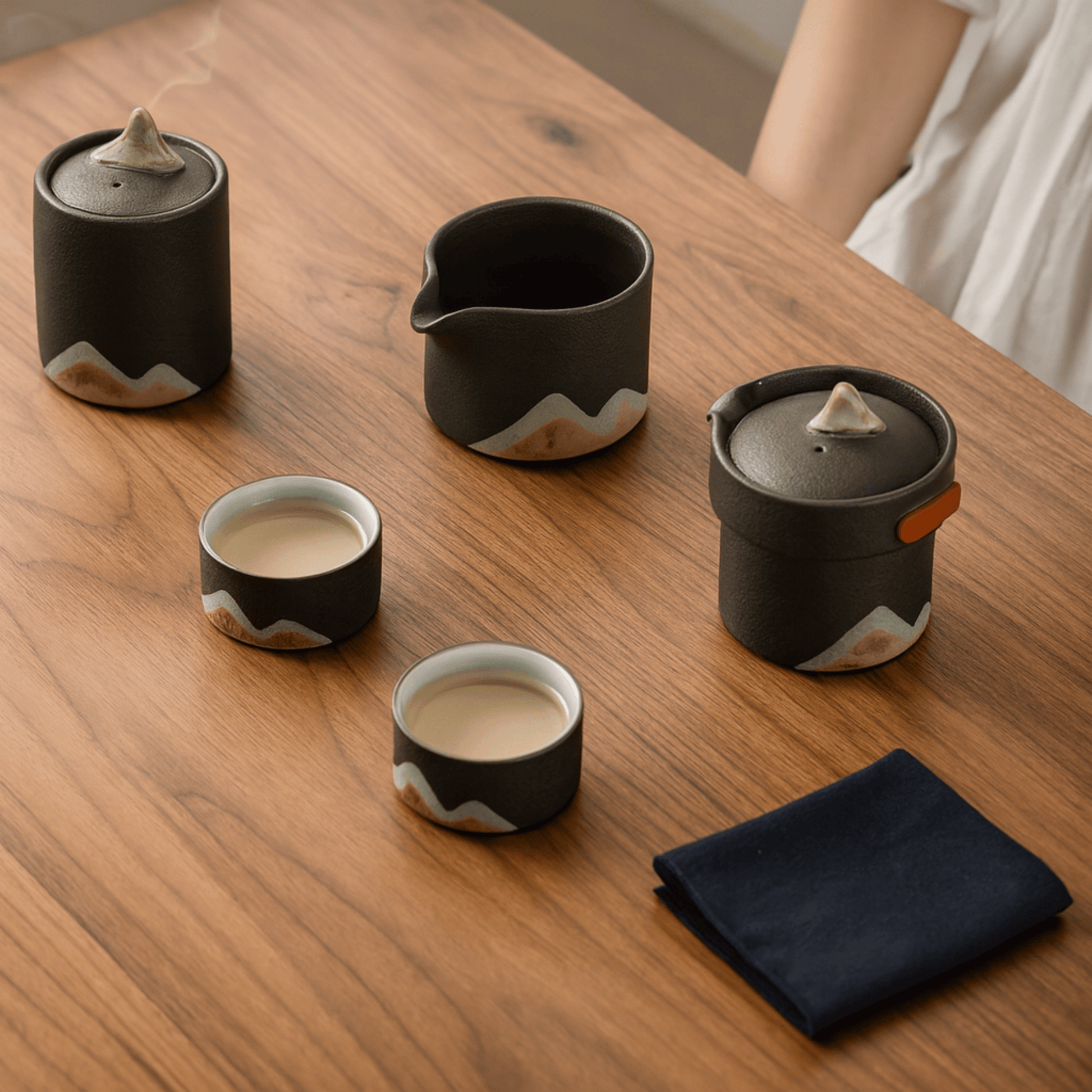 Set of black and white ceramic tea pots and cups on a wooden table.